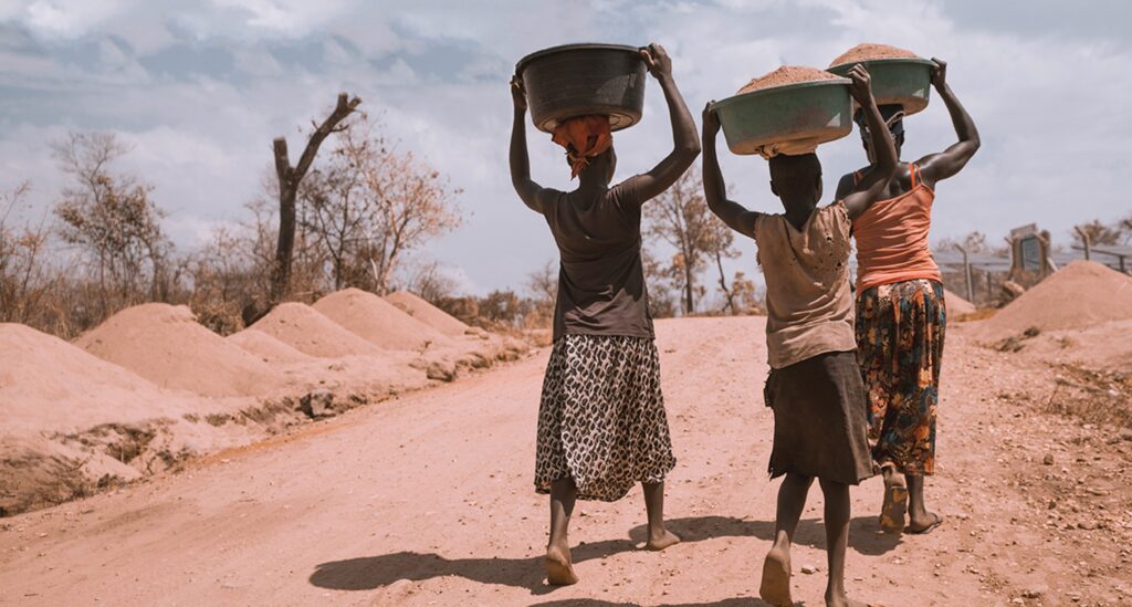 Image: refugee-camp-uganda-three-women-carrying-basins-in-refugee-camp-in-uganda