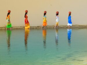 Women carrying jugs of water at the water's age